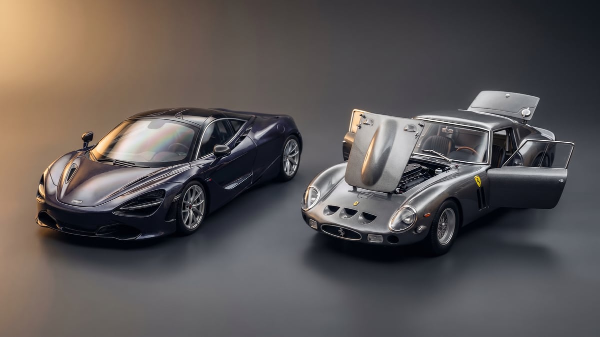 A sealed-resin 1:18 sports car beside a diecast 1:18 model with an open door under studio light
